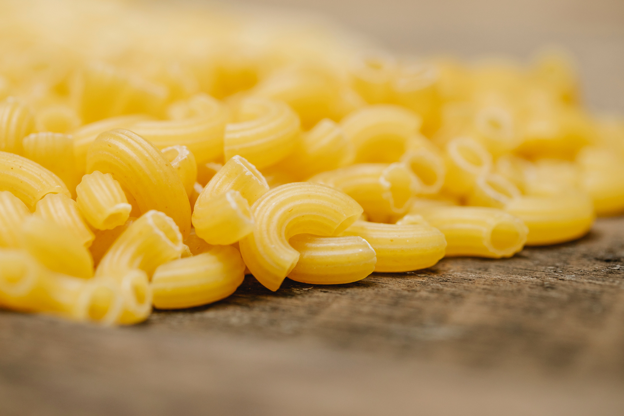 Heap of raw macaroni scattered on wooden table