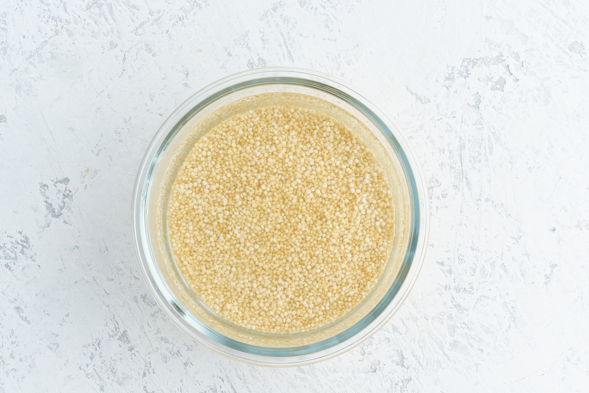 Quinoa Cereal Soaking in Water in a Glass Bowl